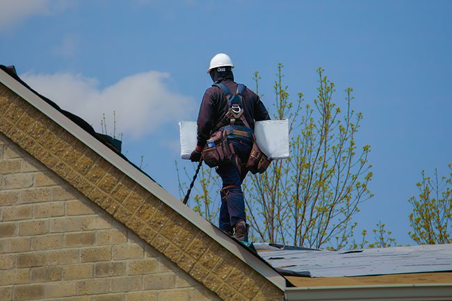 Contractor on roof carrying materials