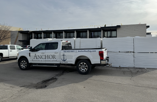 Anchor Roofing work truck with anchor wrap in front of roofing materials
