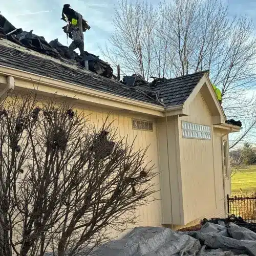 Crew installing impact resistant shingles on a beige residential roof, highlighting advanced roofing solutions by Anchor Roofing