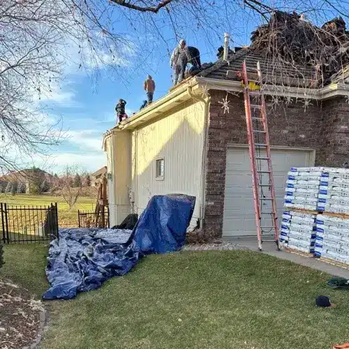Residential roof installation in progress, workers applying impact resistant shingles on a sunny day by Anchor Roofing