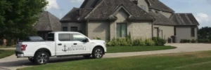 Omaha roofing company Anchor Roofing truck parked in front of a two-story residential home with cedar shake roof
