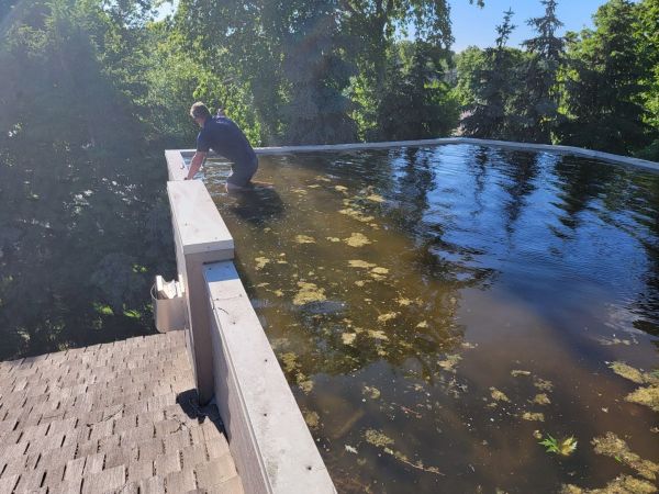 Mike of Anchor Roofing Omaha wades in to address an emergency roof situation in a pool of standing water