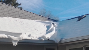 A roof filled with snow that is needing a roofing companies in Omaha