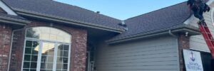 House with black roof and beige siding that had storm damage repair in Omaha