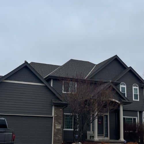 Dark storm clouds and hail falling on a residential roof with impact-resistant shingles