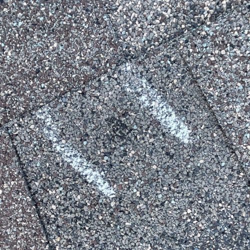 Marked granule loss spot on asphalt shingle showing storm damage in Omaha by Anchor Roofing in Omaha, NE