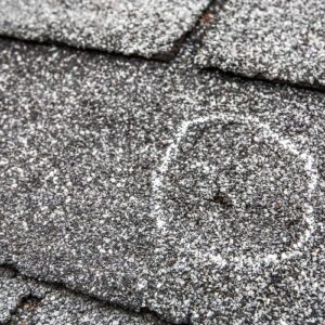 Marked hail impact spot on asphalt shingle roof showing damage by Anchor Roofing in Omaha, NE