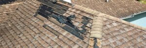 Asphalt shingle roof with severe storm damage and missing sections by Anchor Roofing in Omaha, NE