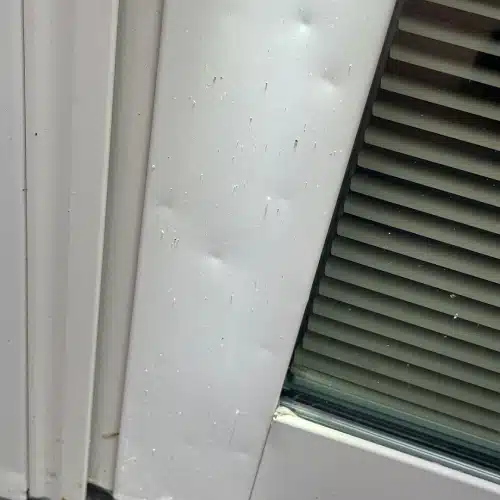 Close-up of dents on a home’s metal door frame in Gretna, NE, caused by hail impact—highlighting typical signs of hail damage that also affects roofs in Omaha.