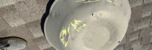 Hail dents and markings on a metal roof vent showing how storms cause roof damage by Anchor Roofing in Omaha, NE