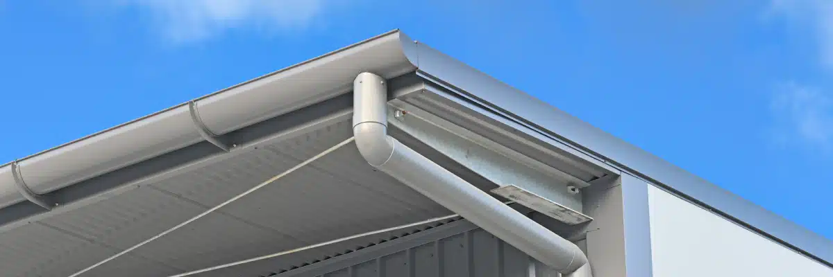 Modern metal commercial gutter system on flat roof, blue sky background, representing professional commercial gutter maintenance in Omaha, NE