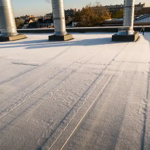 Frost covering a commercial flat roof with metal vent pipes, showing winter risk factors addressed by commercial gutter maintenance in Omaha, NE