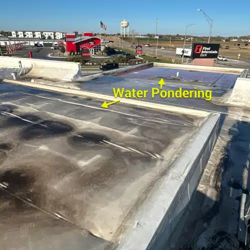 Water ponding on a commercial flat roof above local businesses, highlighting the need for effective commercial gutter maintenance in Omaha, NE