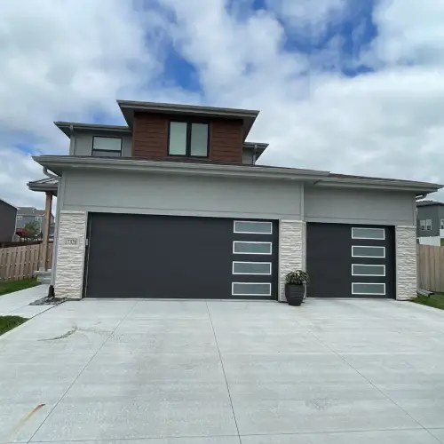 Modern home exterior with contemporary garage doors and clean architectural lines by Anchor Roofing in Omaha, NE