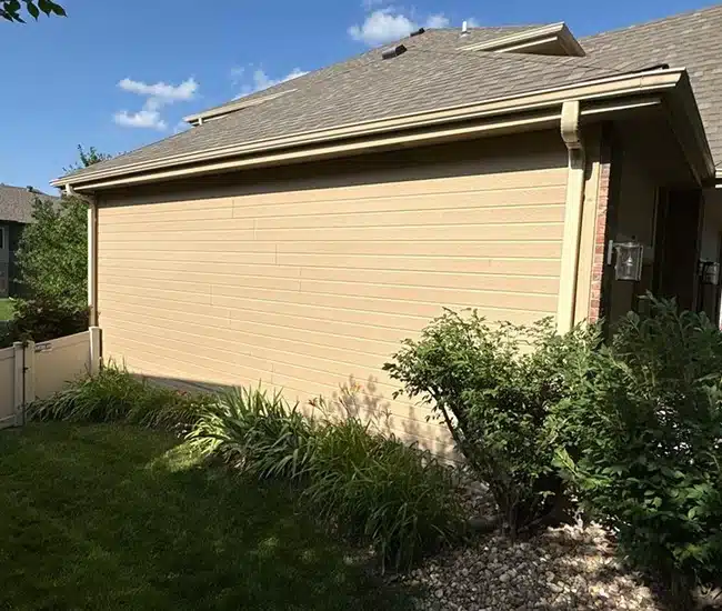Tan siding installation on residential home with landscaped yard by Anchor Roofing in Omaha