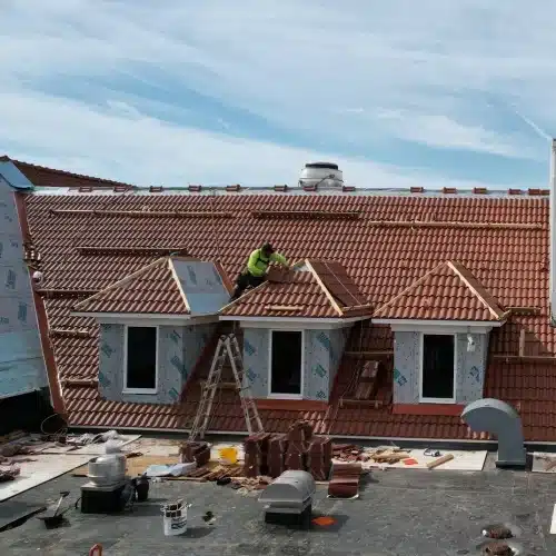 Roofer flashing a dormer and shaping hips while installing Brava Spanish tile at Happy Hollow Country Club, part of an iconic Omaha roof replacement by Anchor Roofing in Omaha