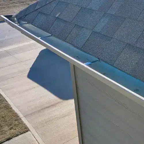 Seamless aluminum gutter mounted along a shingle roof above a driveway—clean lines and pitch for effective gutters in Omaha by Anchor Roofing in Omaha