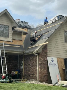 Roofers from Anchor Roofing installing new roofing materials on a residential home in Omaha, working on a steep roof with safety gear and equipment visible.