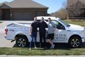 Owens Corning Platinum Preferred Contractor in Omaha team standing beside branded Anchor Roofing truck in a residential neighborhood