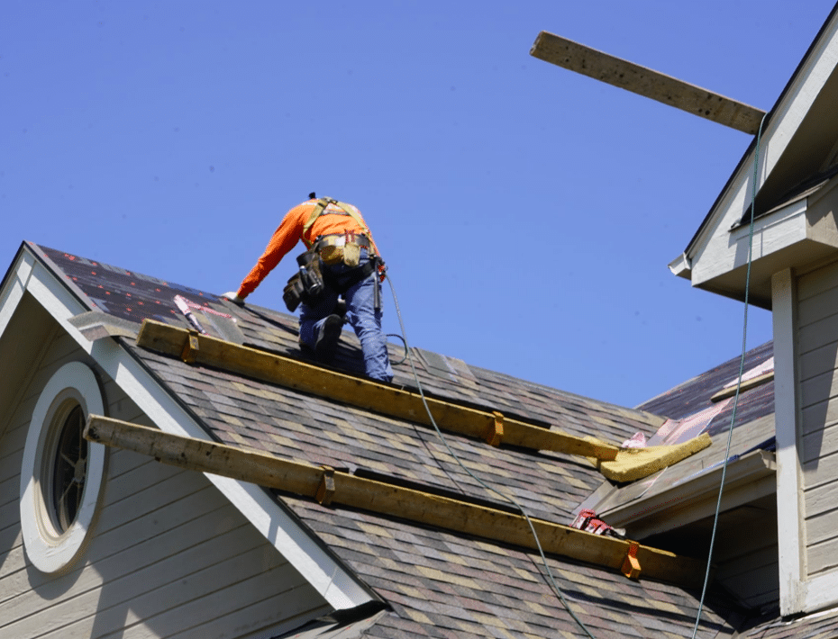 Owens Corning Platinum Preferred Contractor in Omaha roofer installing shingles with safety harness on residential roof under clear blue sky