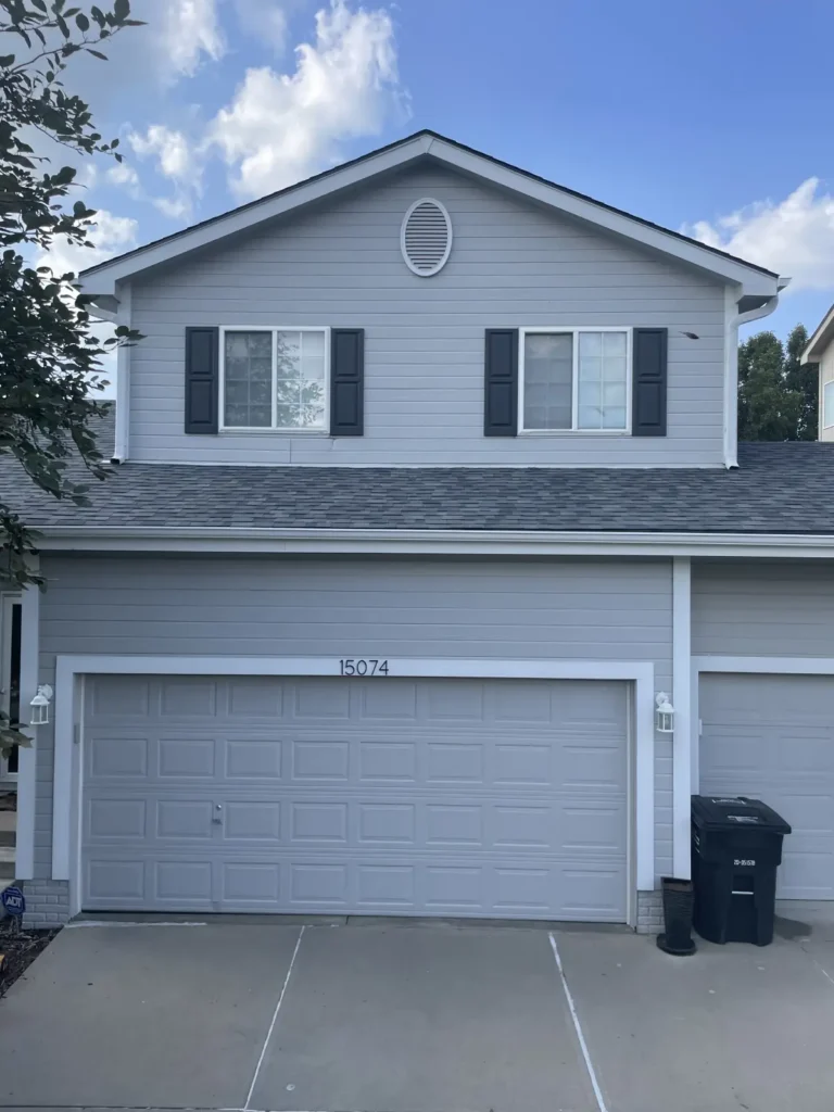 Front view of an Omaha home with gray siding, an attached garage, and a clean asphalt shingle roof completed by Anchor Roofing.