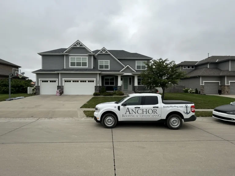 Anchor Roofing company vehicle parked in front of a residential home in Omaha, showcasing a completed roofing project with a newly installed asphalt shingle roof.