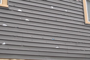 Damaged siding with hail impact marks, supporting siding insurance claims Omaha in Omaha by Anchor Roofing