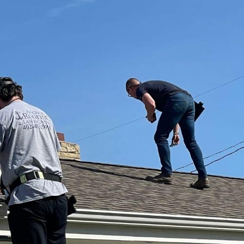 An inspector walking a shingle roof to evaluate wear and document commercial roof maintenance structural needs commercial roof inspection in Omaha by Anchor Roofing