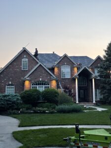 Workers installing underlayment on a steep brick home's roof to comply with roof insurance check rules residential roof replacement in Omaha by Anchor Roofing