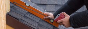 Contractor measuring dark architectural shingles to verify pitch and alignment after proper asphalt shingle storage residential roof installation in Omaha by Anchor Roofing