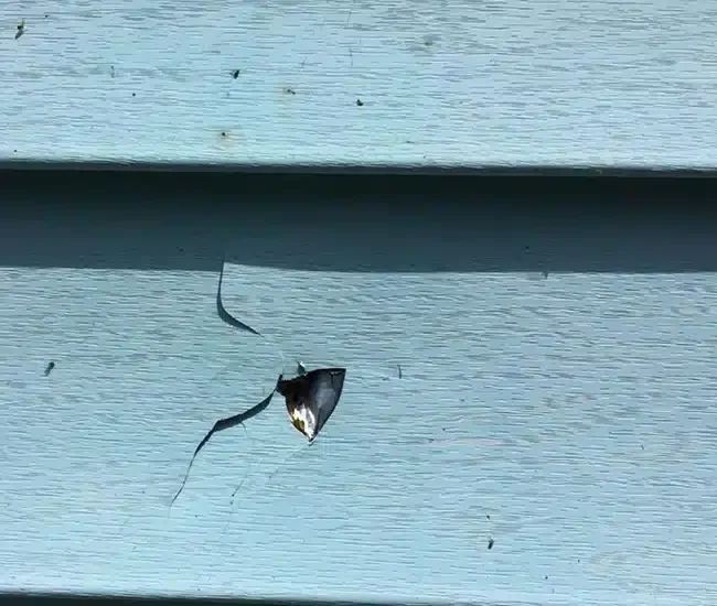 Cracked and damaged vinyl siding highlighting siding contractor repair services by Anchor Roofing in Omaha