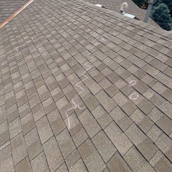 Shingles on top of roof with markings for hail damage