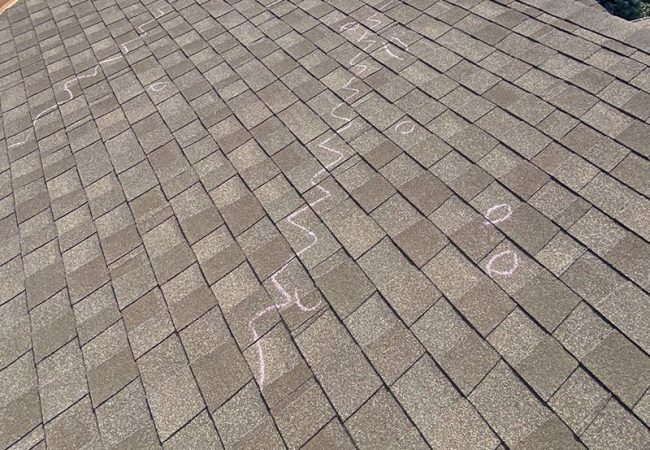 Shingles on top of roof with markings for hail damage