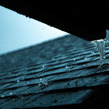 rain pouring from a gutter on to shingles during a hail storm