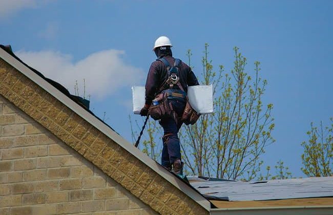 Contractor on roof carrying materials