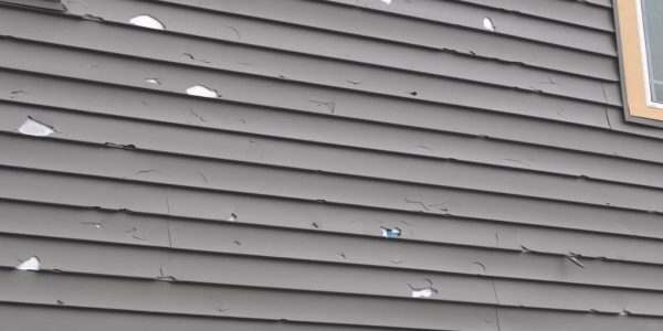 storm damaged siding showing hail impacts and dents in the siding