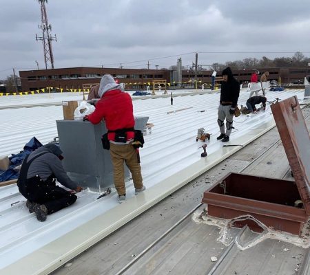 Roofer crew working on top of commercial building to install metal roofing